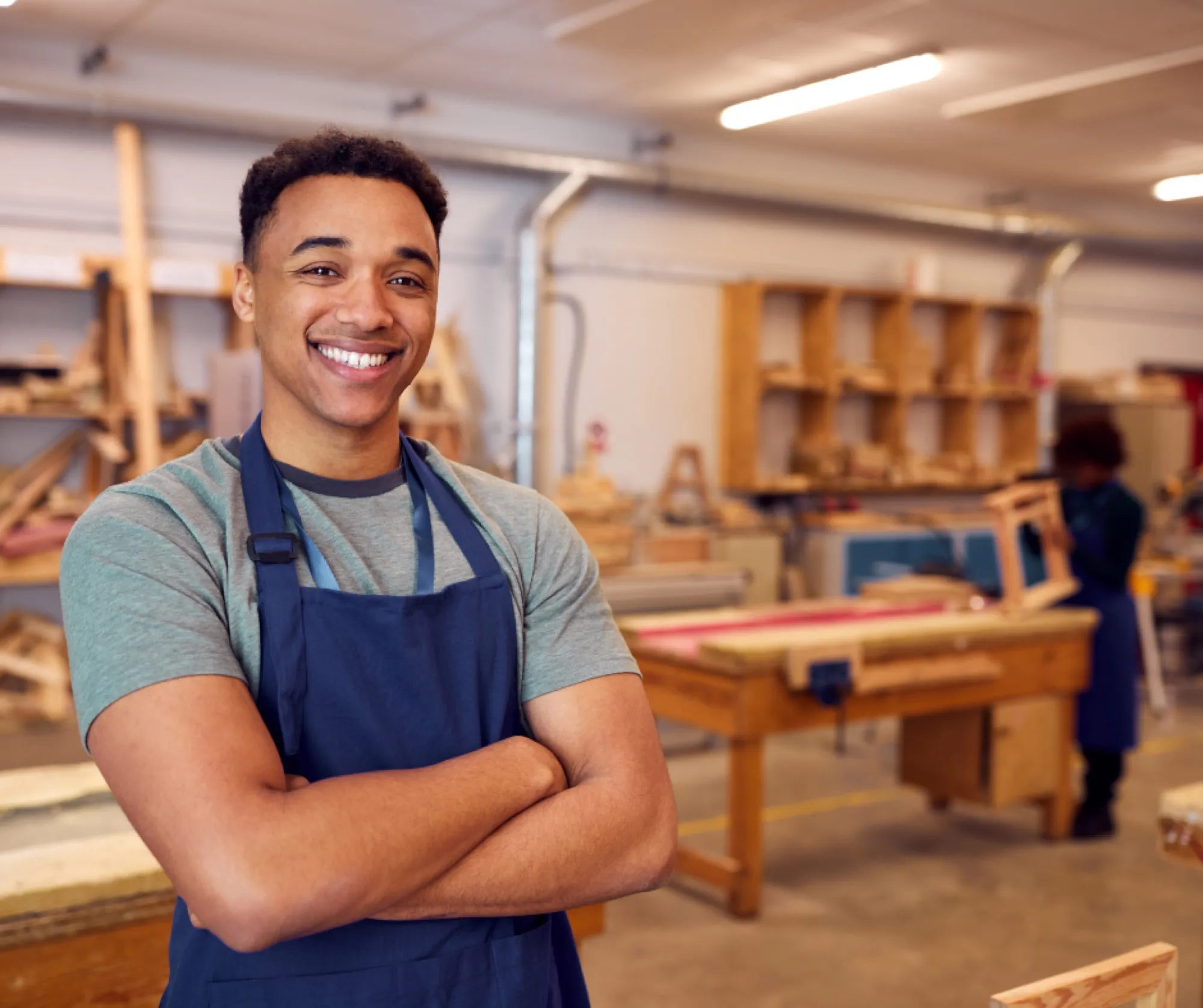 A smiling young man in a workshop apron