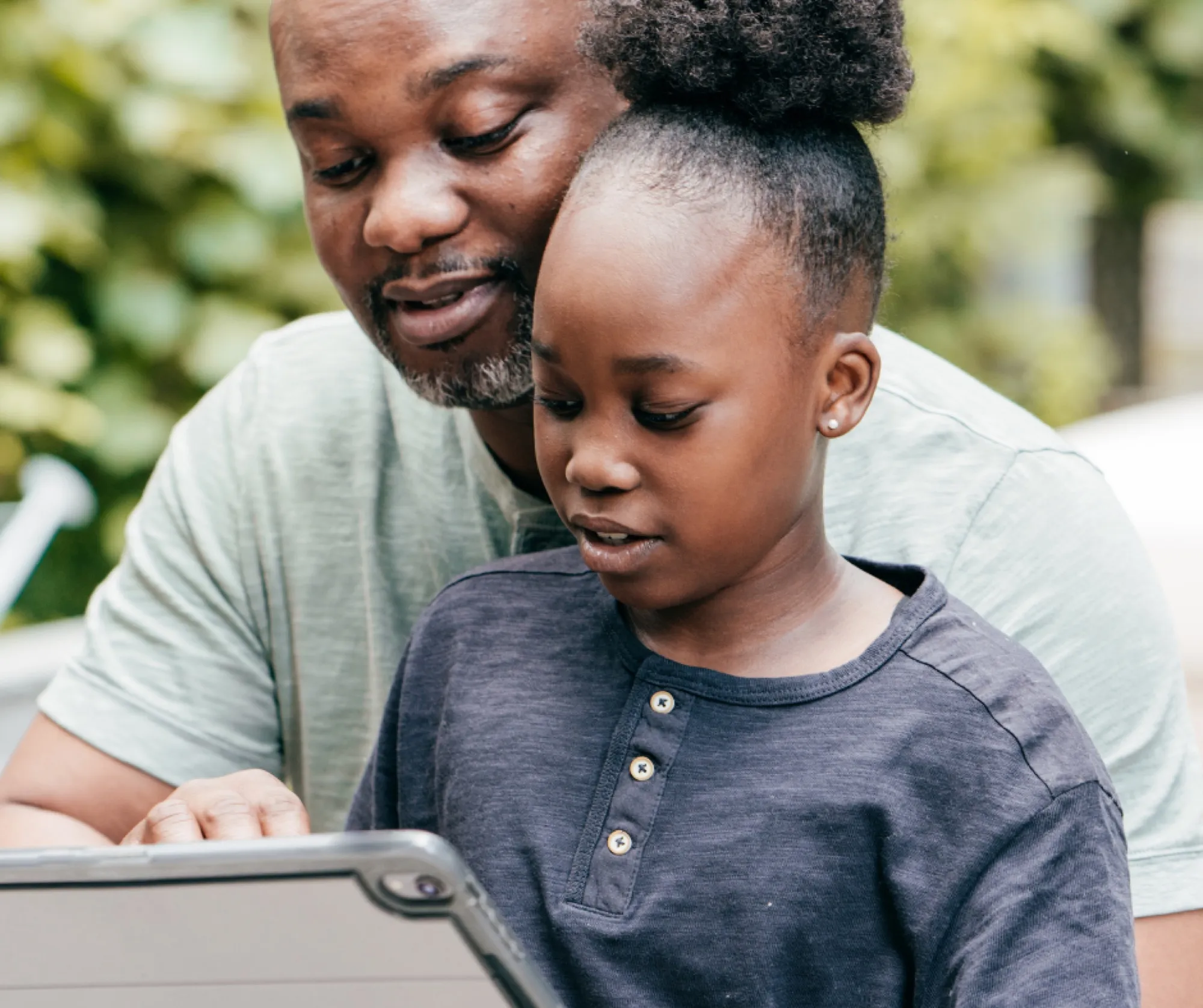 A father helping his daughter with schoolwork on a tablet